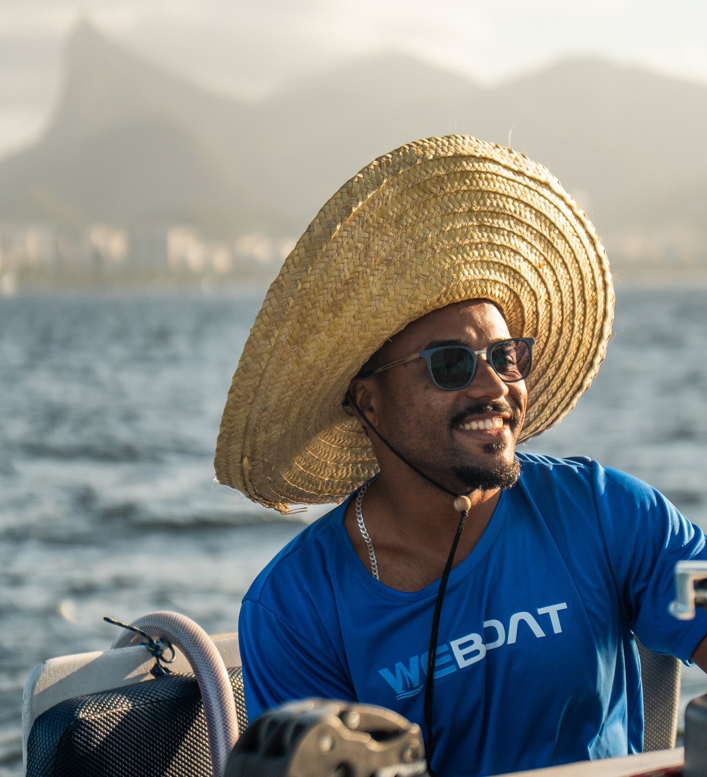 Marinheiro WeBoat com camisa da empresa e Cristo Redentor ao fundo