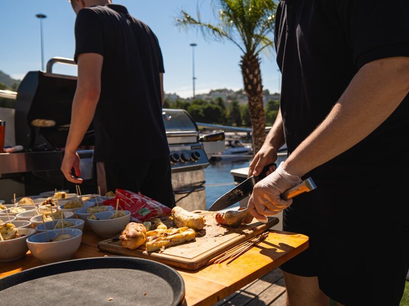 Equipe preparando churrasco e petiscos na churrasqueira da marina com vista para o mar