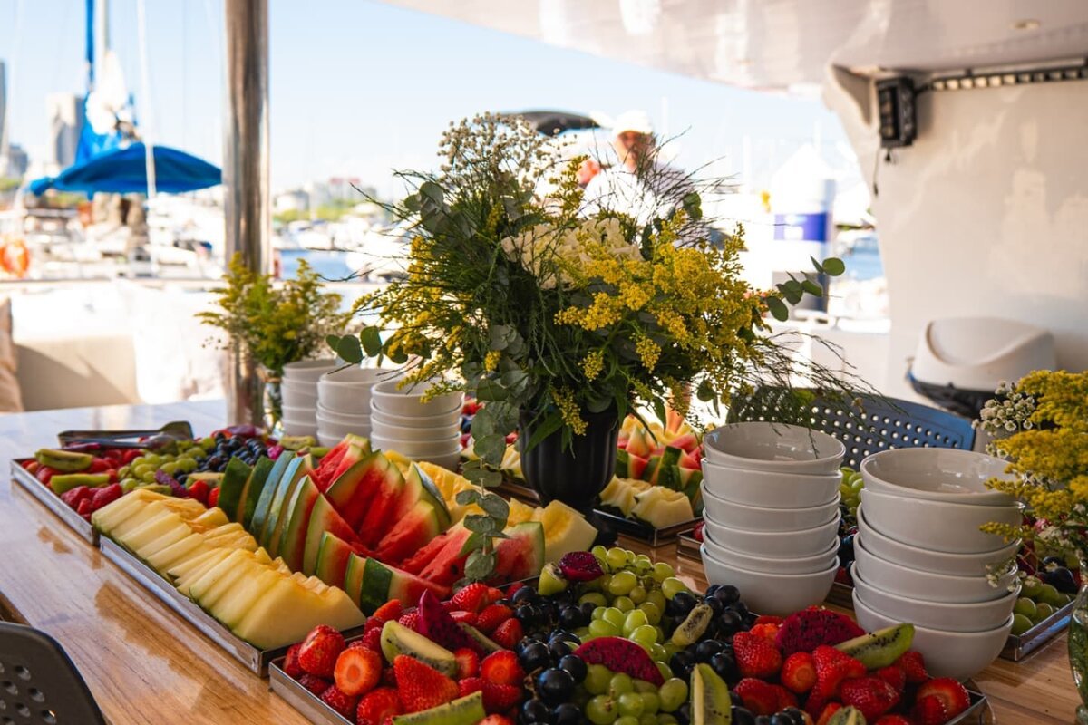 Buffet de frutas tropicais com arranjo de flores na lancha na Marina da Glória
