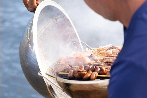 Churrasqueiro preparando espetinhos e carnes na churrasqueira a bordo da lancha