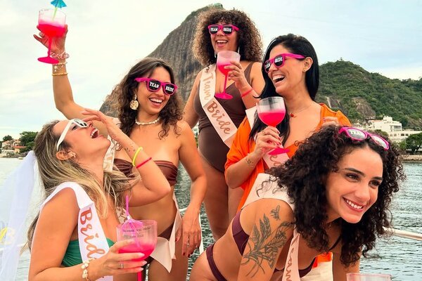 Amigas com faixas Team Bride e drinks rosa na despedida de solteira na lancha