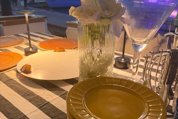 Mesa decorada com pratos, flores e taças para ceia de réveillon na lancha