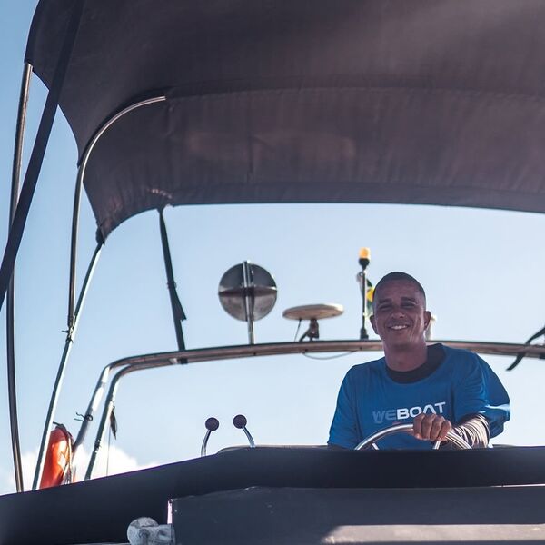 Membro da equipe WeBoat com camisa azul no comando da lancha